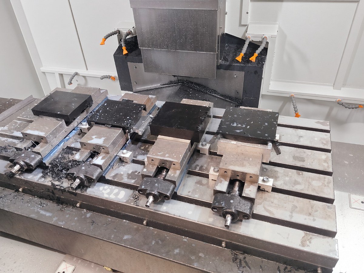 Several parts fixtured in vices on the machining centre table